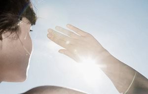 Kvinnan som skyddar ögonen mot solen med sin högra hand.