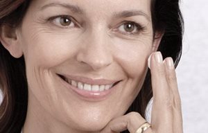 Kvinna som applicerar kräm i ansiktet.