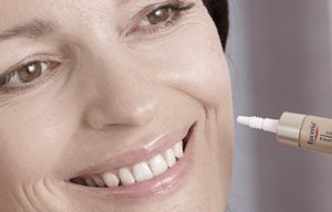 Kvinna som applicerar Eucerin-produkt på sin vänstra kind.