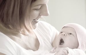 Kvinna som håller en nyfödd baby i famnen.