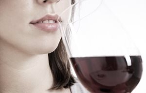 Kvinna som dricker ett glas rött vin.