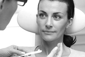 Hudläkare som applicerar hudkräm i en patients ansikte