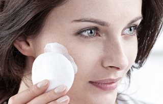 Kvinna som applicerar Cleansing Milk på en bomullsrondell