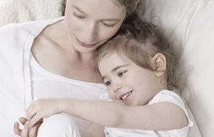 Mor och barn sitter tätt ihopkrupna och myser.