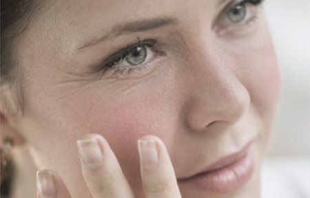 Kvinna som rör vid ansiktet med handen